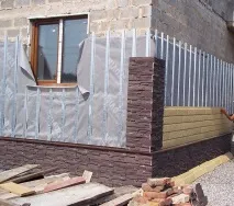 Облицювання фасаду будинку пластиковими панелями під камінь. пластиковими